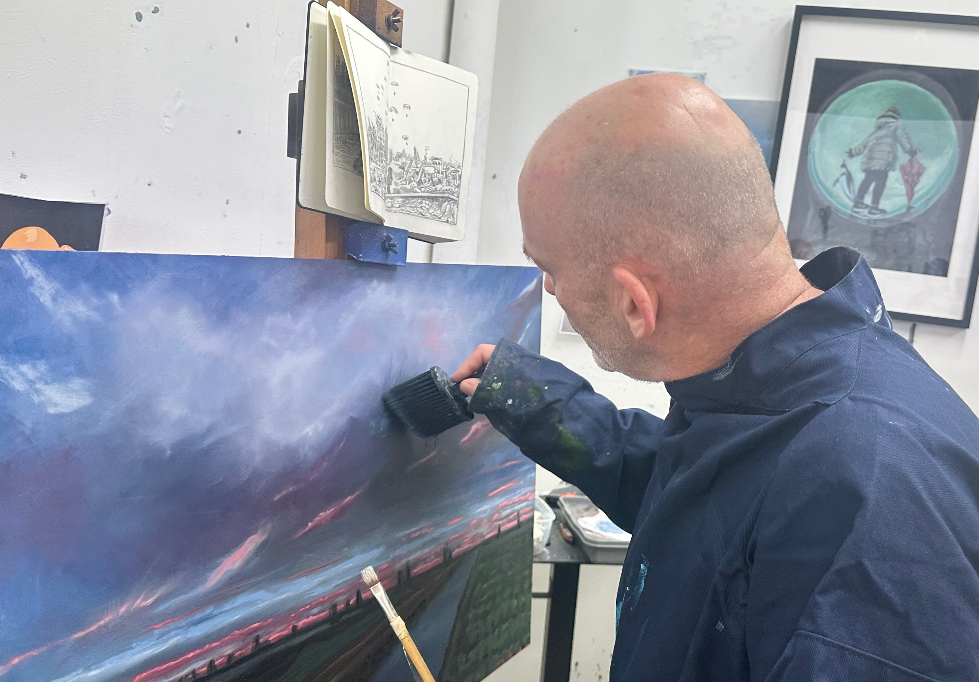 Michael Epton painting a large canvas in an art studio with various artworks on the walls.